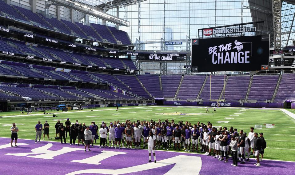 Minnesota Vikings stadium with players huddled near end zone and "Be The Change" on the videoboard.