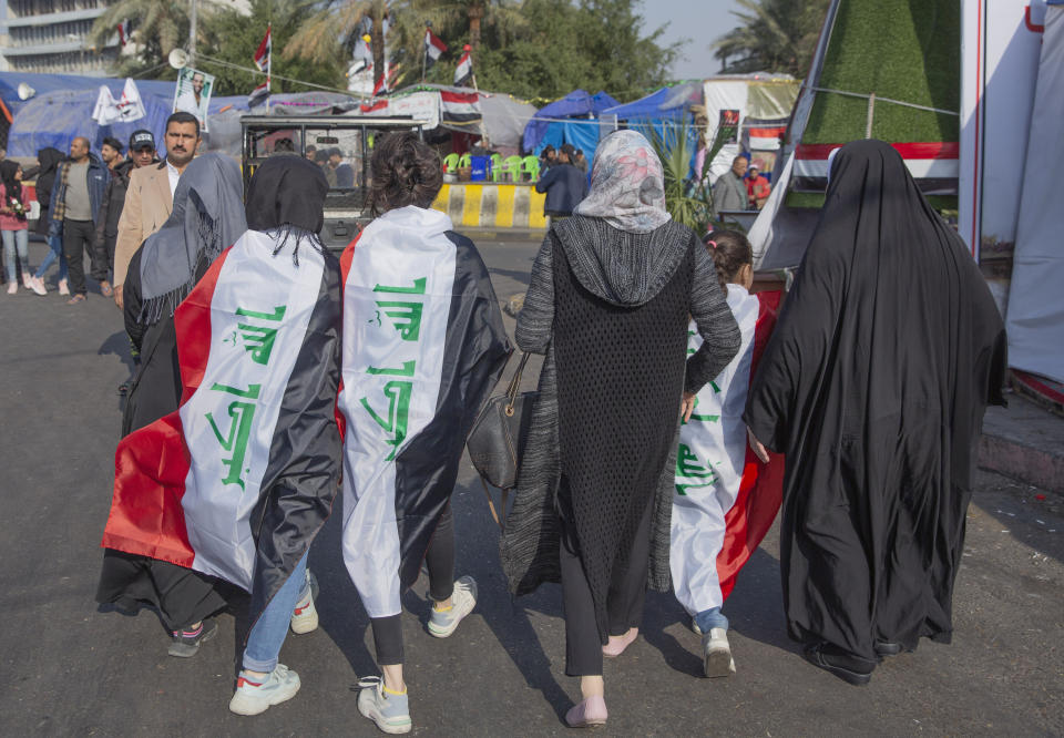 Women are wrapped the Iraqi flags during the ongoing protests in Tahrir Square, Baghdad, Iraq, Thursday, Dec. 26, 2019. (AP Photo/Nasser Nasser)