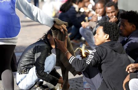 Dejen Asefaw (R), a 24-year-old Eritrean, receives a pullover from a volunteer at the Bolzano railway station, northern Italy, May 28, 2015. REUTERS/Stefano Rellandini