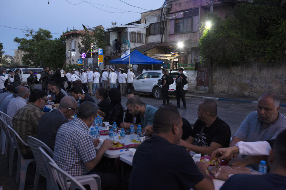 Israeli police stand guard as Palestinian Muslims break their fast during the holy month of Ramadan and Jewish settlers gather to begin Shabbat at a Palestinian house occupied by settlers, in the Sheikh Jarrah neighborhood of east Jerusalem, Friday, May 7, 2021. Dozens of Palestinian families in east Jerusalem are at risk of losing their homes to Jewish settler groups following a decades-long legal battle. The threatened evictions have sparked weeks of protests and clashes in recent days, adding to the tensions in Jerusalem. (AP Photo/Maya Alleruzzo)