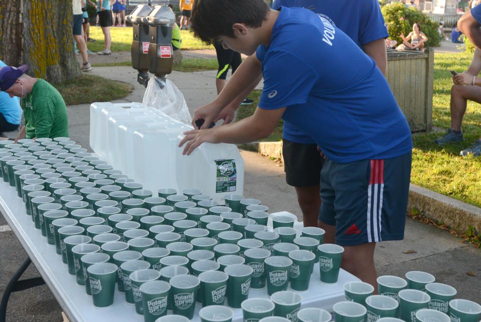 Jack Balfour keeps up with the demand in Woods Hole at a water stop at the 50th running of the Falmouth Road Race.