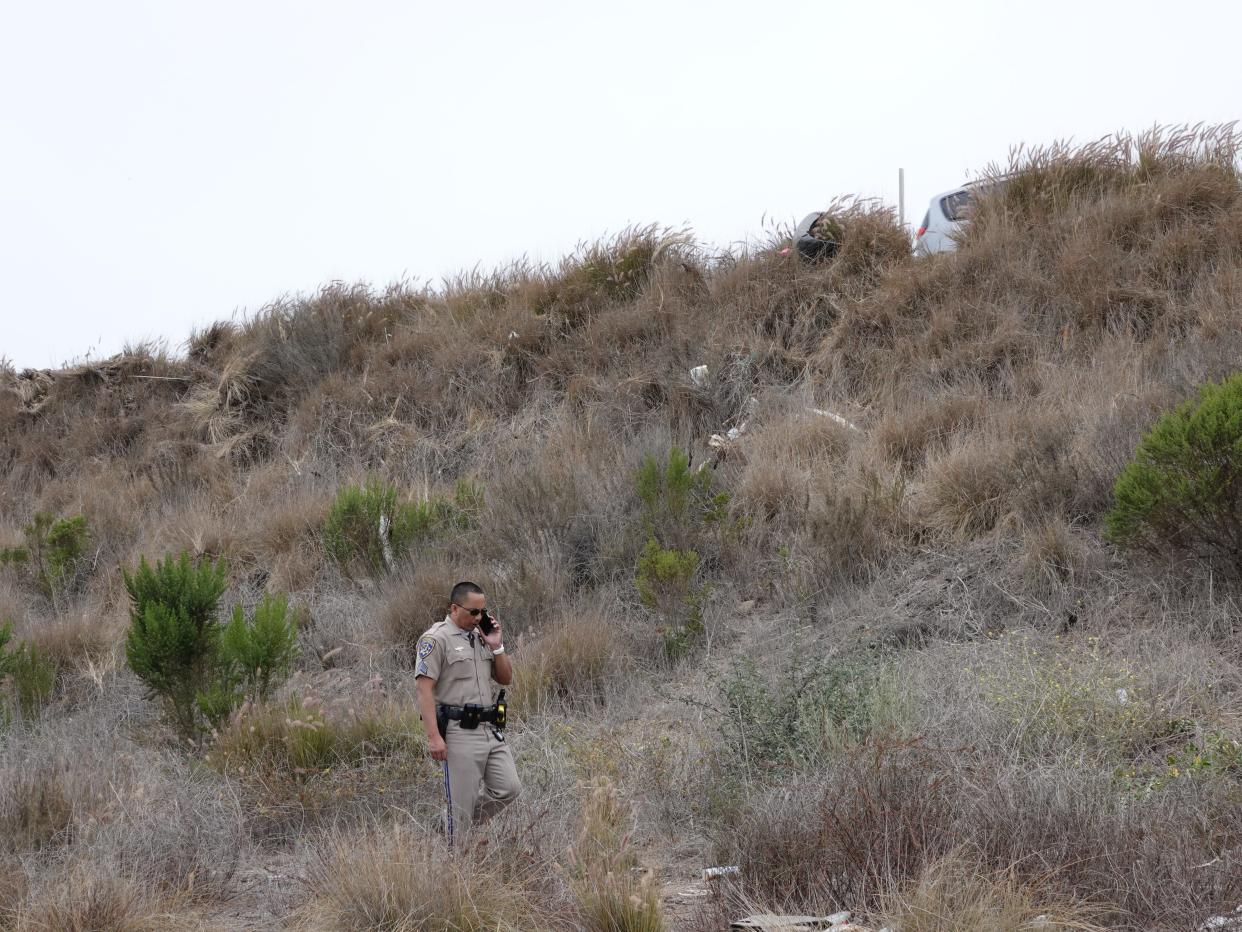 California Highway Patrol Sgt. Michael Untalan inspects a fatal crash scene on an embankment along southbound Highway 101 in Ventura on June 20, 2021. On Thursday, the driver pleaded guilty to felony DUI charges.