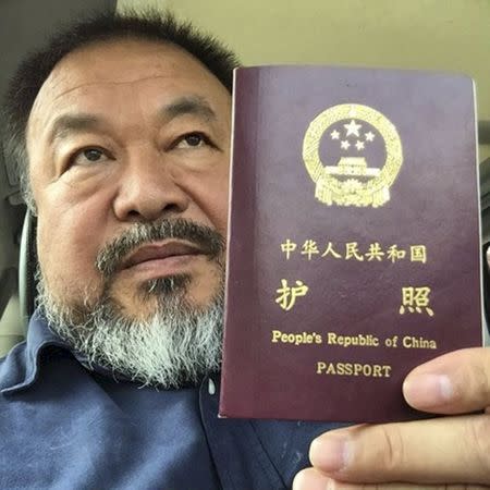 Chinese dissident artist Ai Weiwei poses with his passport in Beijing in this handout picture provided to Reuters on July 22, 2015. Chinese dissident artist and free speech advocate Ai Weiwei said that authorities in Beijing returned his passport on Wednesday, more than four years after it was confiscated following his 81-day secret detention. REUTERS/Ai Weiwei/Handout via Reuters