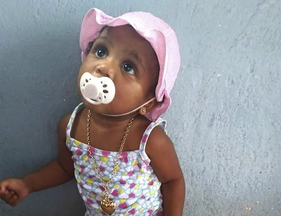 In this Feb. 10, 2020, photo, provided by Andréa de Sousa, her daughter Vitoria Gabrielle looks up while leaning against a wall, in Rio de Janeiro, Brazil. The girl with a constant smile celebrated her first birthday in February, but after recovering from viral meningitis, Vitoria Gabrielle suffered gastrointestinal problems that sent her from her mother's barely furnished hilltop home back to the hospital several times for treatment. It was during an April hospital stay that de Sousa suspects her daughter was infected with the coronavirus that was just starting to circulate in Rio and Brazil. Vitoria Gabrielle died in June. (Courtesy of Andréa de Sousa via AP)