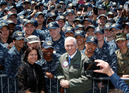 U.S. Vice President Mike Pence, flanked by his wife Karen, poses for photos with U.S service members as he visits the USS Ronald Reagan, a Nimitz-class nuclear-powered super carrier, at the U.S. naval base in Yokosuka, south of Tokyo, Japan April 19, 2017. REUTERS/Kim Kyung-Hoon