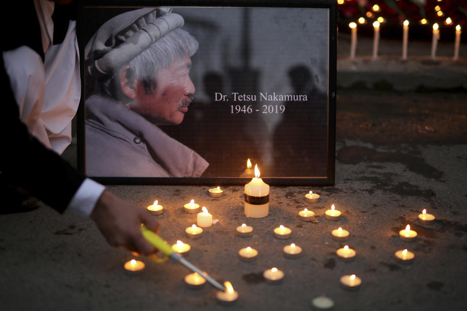 An Afghan man lights a candle in front of a portrait of Tetsu Nakamura, a Japanese physician engaged in aid work who was killed Wednesday, Dec. 4 in a shooting in eastern Afghanistan, during a vigil in Kabul, Afghanistan on Thursday, Dec. 5, 2019. (AP Photo/Altaf Qadri)