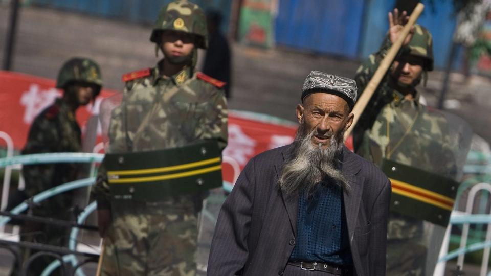 Ein Angehöriger der uigurischen Minderheit in der Unruheregion Xinjiang in Nordwestchina geht vorbei an chinesischen Sicherheitskräften.