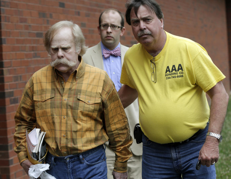 FILE - In this June 10, 2013, file photo, Harvey Updyke, left, departs the Lee County Justice Center in Opelika, Ala.,  with his bail bondsman and his attorney. The state's football fervor drew plenty of attention after the 2010 Iron Bowl, when Updyke, an Alabama fan, poisoned Auburn's two iconic oak trees at Toomer's Corner, whose branches were decorated with toilet paper during victory celebrations for decades. (AP Photo/Dave Martin, File)