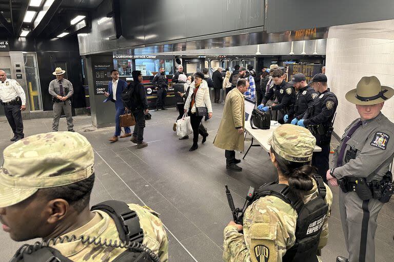 Miembros de las Fuerzas Armadas, incluida la Guardia Nacional, patrullan el sistema de metro en Penn Station mientras los agentes de policía revisan los bolsos de los viajeros en Nueva York 