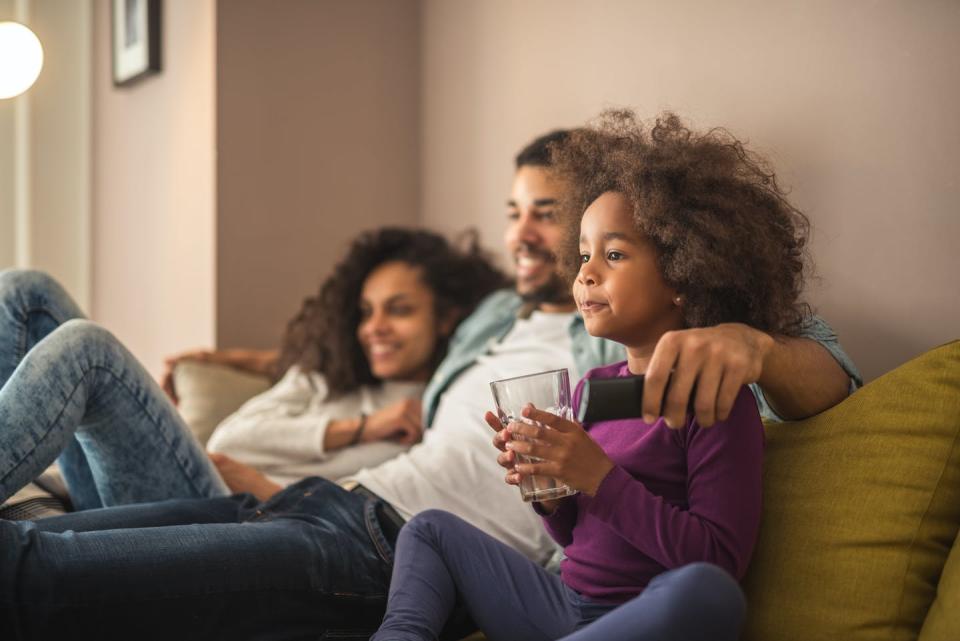 A young girl watching television with her parents