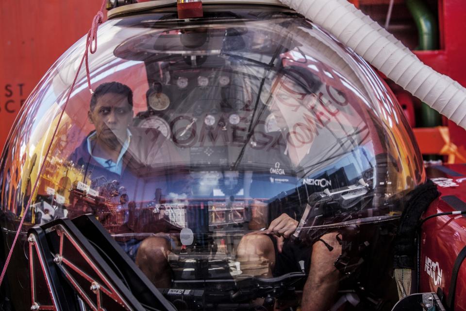 In this Saturday, April 13, 2019, photo, Seychelles President Danny Faure, left, sits inside a submersible on the deck of vessel Ocean Zephyr, off the coast of Desroches, in the outer islands of Seychelles. Faure toured the vessel and was presented with some of the findings and observations made by a British-led science expedition documenting changes taking place beneath the waves that could affect billions of people in the surrounding region over the coming decades. (AP Photo/Steve Barker)