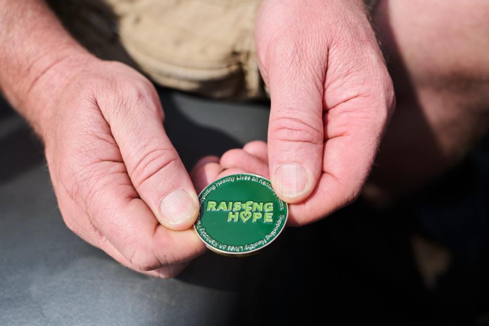 A Harrison County, Kentucky, farmer holds a coin given to him by the Raising Hope organization, which aims to bring awareness to the mental health of Kentucky farmers. Aug. 9, 2023