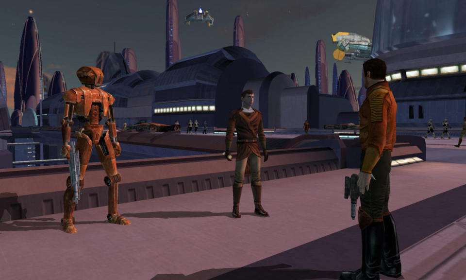 A still from Star Wars: Knights of the Old Republic.  The two and his droid are standing on a bridge in a very Star Wars-like environment. buildings, ships, towers.