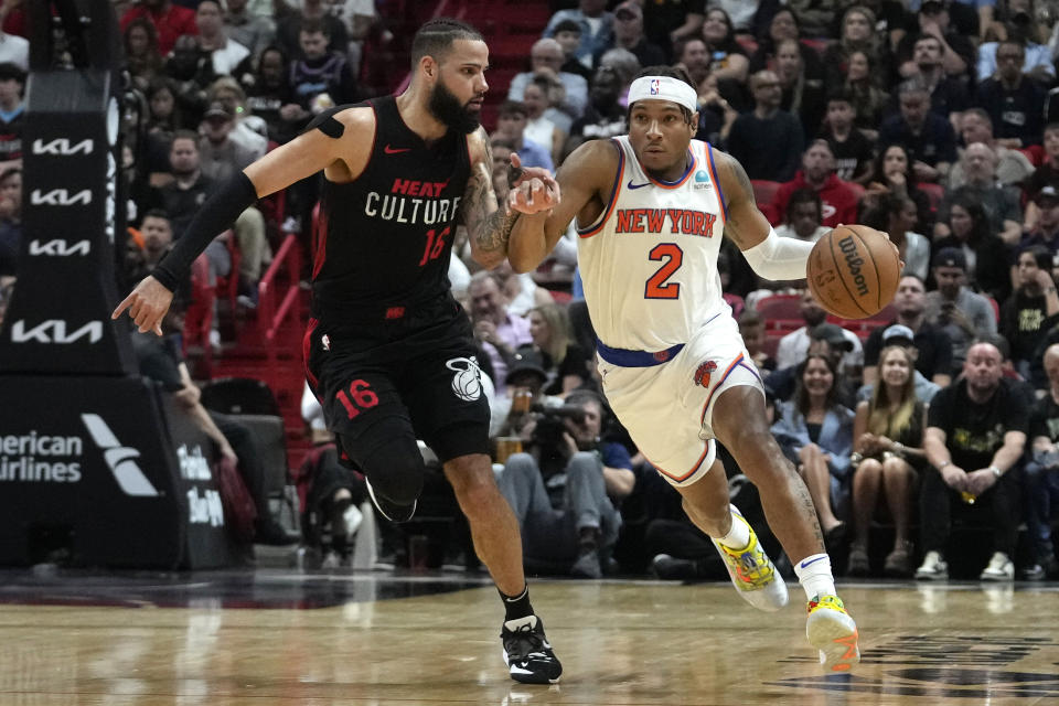 New York Knicks guard Miles McBride (2) moves the ball down the court as Miami Heat forward Caleb Martin (16) defends during the first half of an NBA basketball game, Tuesday, April 2, 2024, in Miami. (AP Photo/Lynne Sladky)