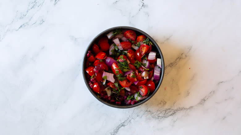 pomegranate, cherry tomatoes, onions and cilantro in bowl