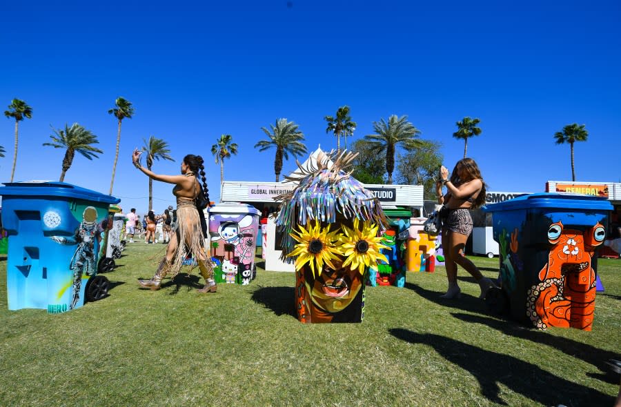 Festivalgoers take pictures with decorated trash cans during the Coachella Valley Music and Arts Festival in Indio, California, on April 14, 2024. (Photo by VALERIE MACON / AFP) (Photo by VALERIE MACON/AFP via Getty Images)