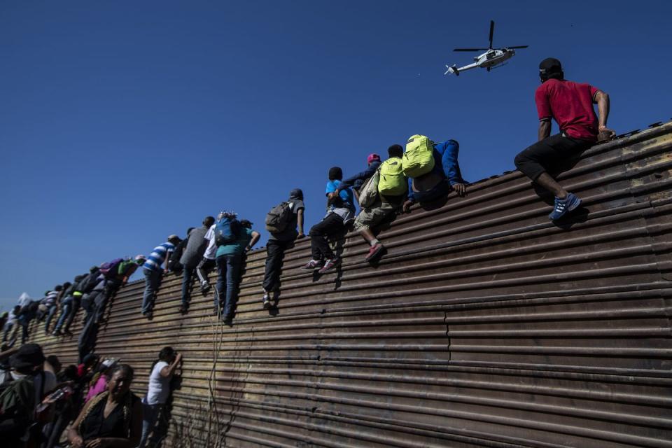 <p>A group of Central American migrants -mostly Hondurans- climb a metal barrier on the Mexico-US border near El Chaparral border crossing, in Tijuana, Baja California State, Mexico, on November 25, 2018.</p>