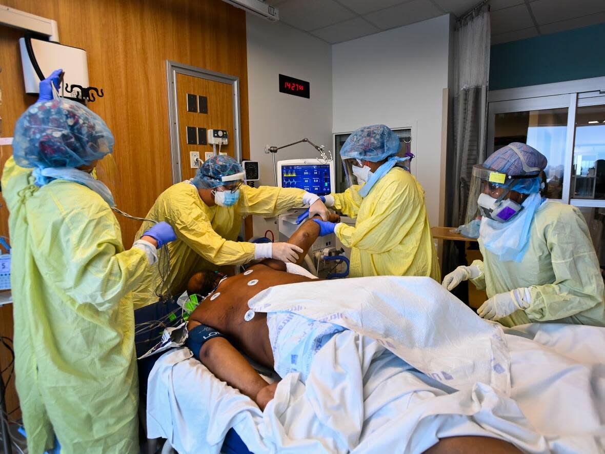 This file photos shows medical staff in the ICU at the Humber River Hospital in Toronto turn a COVID-19 patient who is intubated and on a ventilator from his back to his stomach. (Nathan Denette/The Canadian Press - image credit)