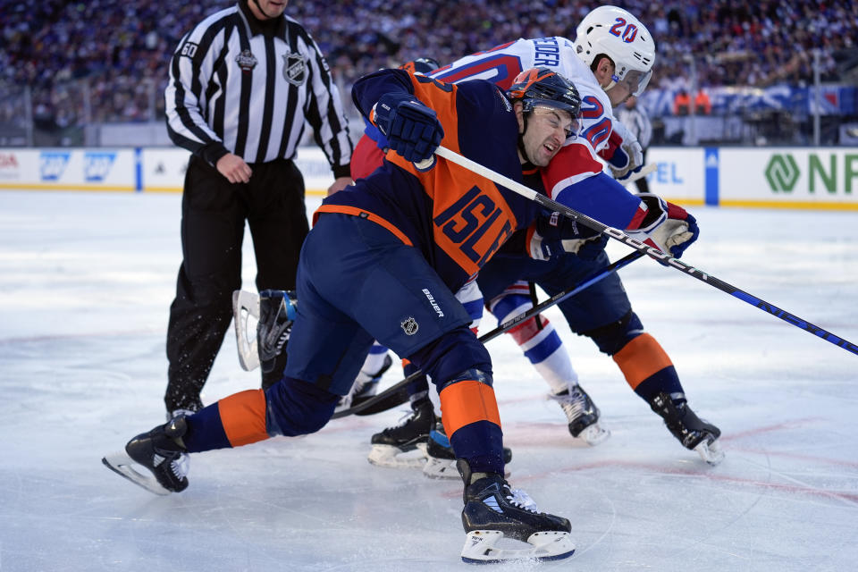 New York Rangers' Chris Kreider (20), right, and New York Islanders' Adam Pelech, front, fight for the puck during the first period of an NHL Stadium Series hockey game in East Rutherford, N.J., Sunday, Feb. 18, 2024. (AP Photo/Seth Wenig)
