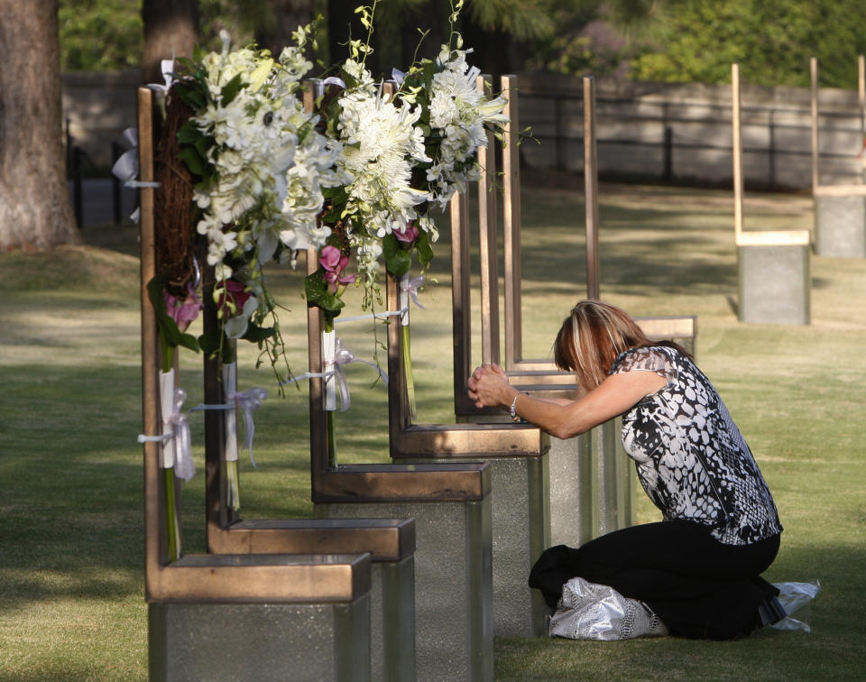 FILE - In this April 19, 2011 file photo shows Regina Bonny, a retired Midwest City, Okla., police officer from Moore, Okla., at the chair of DEA agent Kenneth Glenn McCullough in the field of chairs at the Oklahoma City National Memorial and Museum in Oklahoma City on the 16th anniversary of the Oklahoma City bombing. The memorial is where visitors can pay tribute to the people who were killed and those who survived the bombing at the Alfred P. Murrah Federal Building on April 19, 1995. While the Memorial Museum has an admission fee, the outdoor memorial, full of symbolism, is free and open year round. (AP Photo/Sue Ogrocki, File)