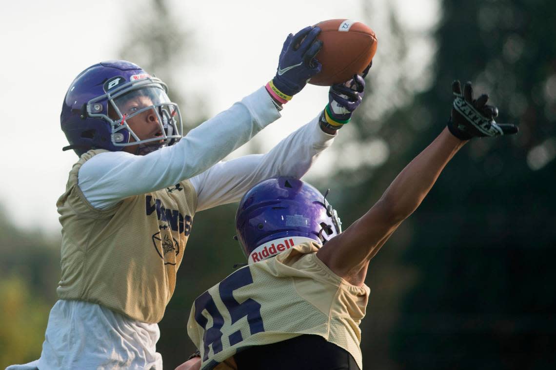 Puyallup High School wide receiver and defensive back Malachi Durant jumps up and catches a pass over a teammate during a drill at practice on Friday, Aug. 19, 2022 at Sparks Stadium in Puyallup, Wash.