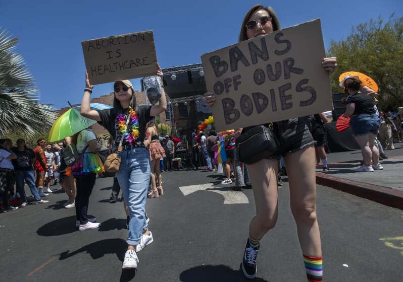 Rachel Esconde, left, of Anaheim, and Chantalle Sheung, right, of Anaheim, came prepared for the OC Pride Parade and Festival to show what they think about the recent Supreme Court ruling in Santa Ana on Saturday, June 25, 2022. (Photo by Paul Rodriguez)