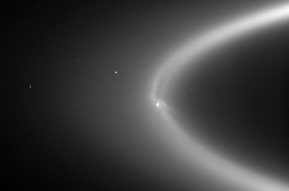 Saturn's moon Enceladus (center right) blasts material into the planet's E ring. <cite>NASA/JPL/Space Science Institute</cite>