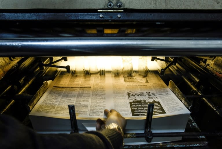 A technician retrieves for inspection a freshly-printed page of the Afrika newspaper