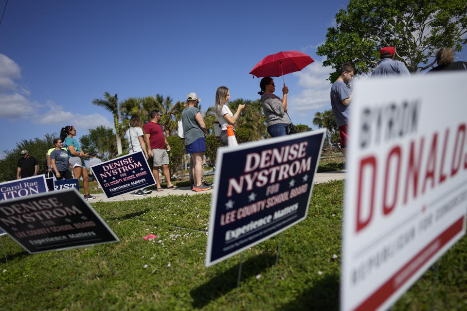 FILE - Lee County voters stand beside campaign signs as they wait in line to cast their ballots at Northeast Regional Library in Cape Coral, Fla, on Election Day, Tuesday, Nov. 8, 2022. (AP Photo/Rebecca Blackwell, File)