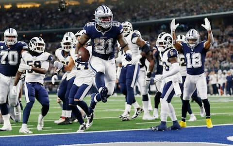 Dallas Cowboys running back Ezekiel Elliott (21) jumps into the end zone with a touchdown in front of Los Angeles Rams defensive back Darious Williams (31) in the first half an NFL football game in Arlington, Texas - Credit: AP