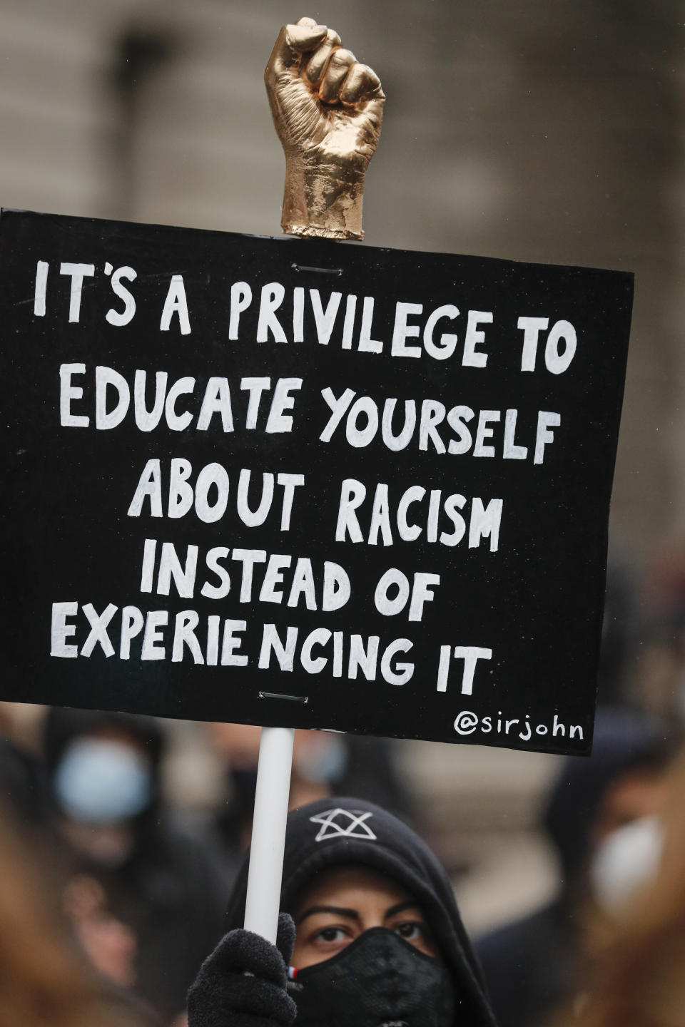 FILE - In this Saturday, June 6, 2020 file photo, a demonstrator holds a placard, during a Black Lives Matter rally in Parliament Square in London, Saturday, June 6, 2020, as people protest against the killing of George Floyd by police officers in Minneapolis, USA. There is racism in Britain, but it’s not a systematically racist country that is “rigged” against non-white people. That’s the conclusion, published Wednesday, March 31, 2021 of an inquiry commissioned by the Conservative government in the wake of anti-racism protests across the country last year. Many ethnic-minority Britons greeted that claim with skepticism, saying the inquiry's 264-page report downplayed the discrimination and disadvantage they face. (AP Photo/Frank Augstein, File)