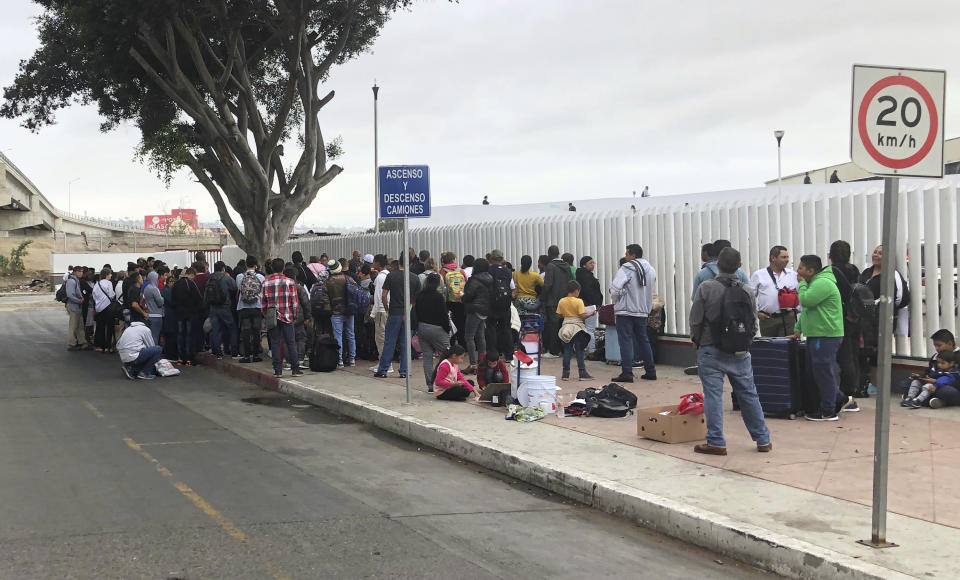 Asylum seekers in Tijuana, Mexico, listen to names being called from a waiting list to claim asylum at a border crossing in San Diego, Thursday, Sept. 26, 2019. The Trump administration played "bait and switch" by instructing migrants to wait in Mexico for an opportunity to apply for asylum before imposing sharp restrictions on eligibility, attorneys said in a court filing Thursday. (AP Photo/Elliot Spagat)