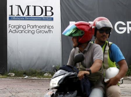 Motorcyclists pass a 1Malaysia Development Berhad (1MDB) billboard at the Tun Razak Exchange development in Kuala Lumpur, Malaysia, February 3, 2016. REUTERS/Olivia Harris/File Photo