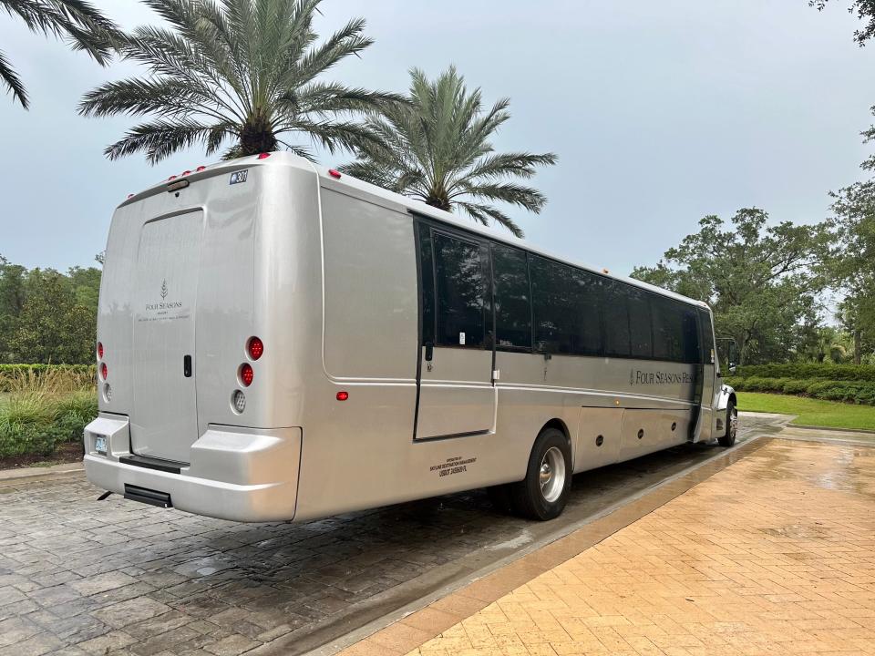 Silver motorcoach parked in front of palm trees