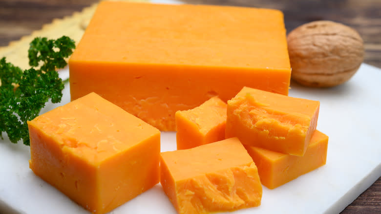 Chunks of orange cheese on white board 