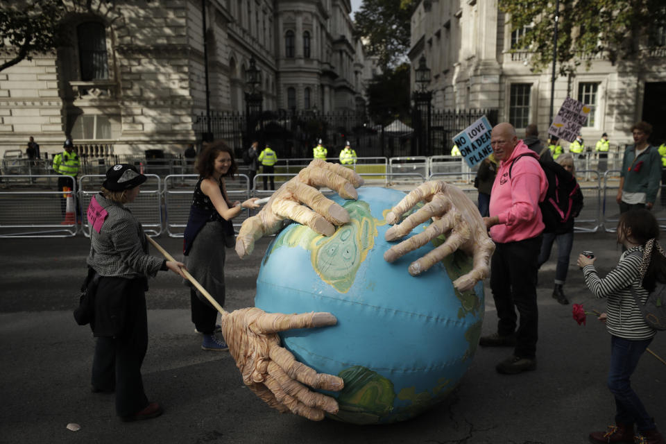 Extinction Rebellion climate change protesters demonstrate backdropped by the front gates of Downing Street in London, Tuesday, Oct. 8, 2019. Hundreds of climate change activists camped out in central London on Tuesday during a second day of world protests by the Extinction Rebellion movement to demand more urgent actions to counter global warming. (AP Photo/Matt Dunham)
