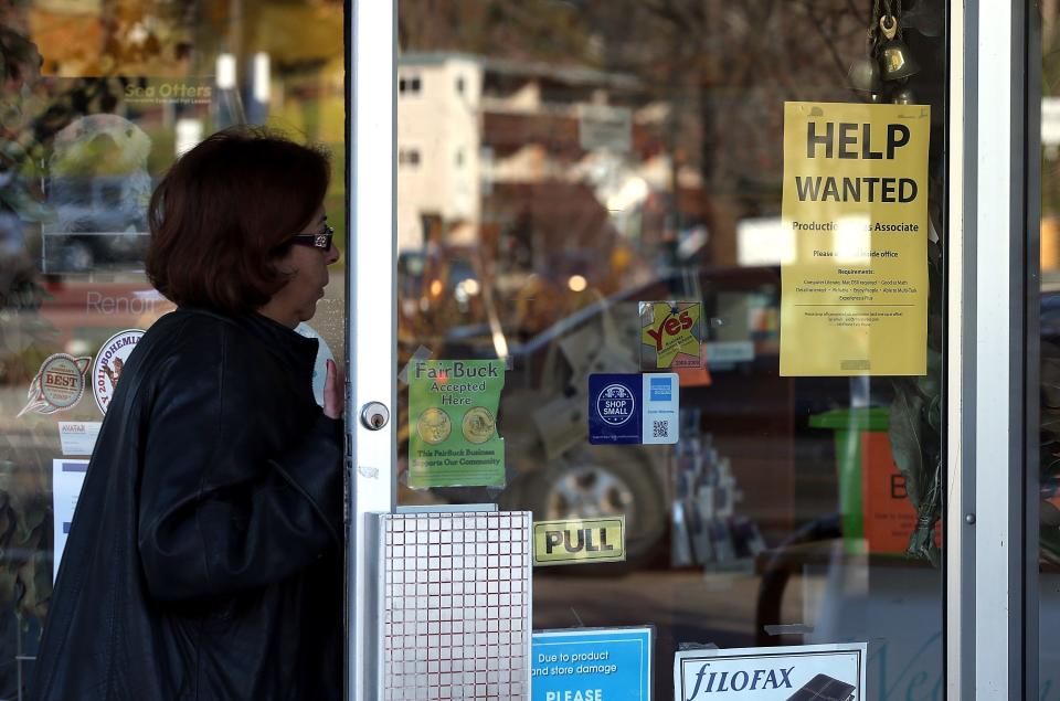 A woman walks into a store with a help wanted sign posted on the door on January 4, 2013 in Fairfax, California.