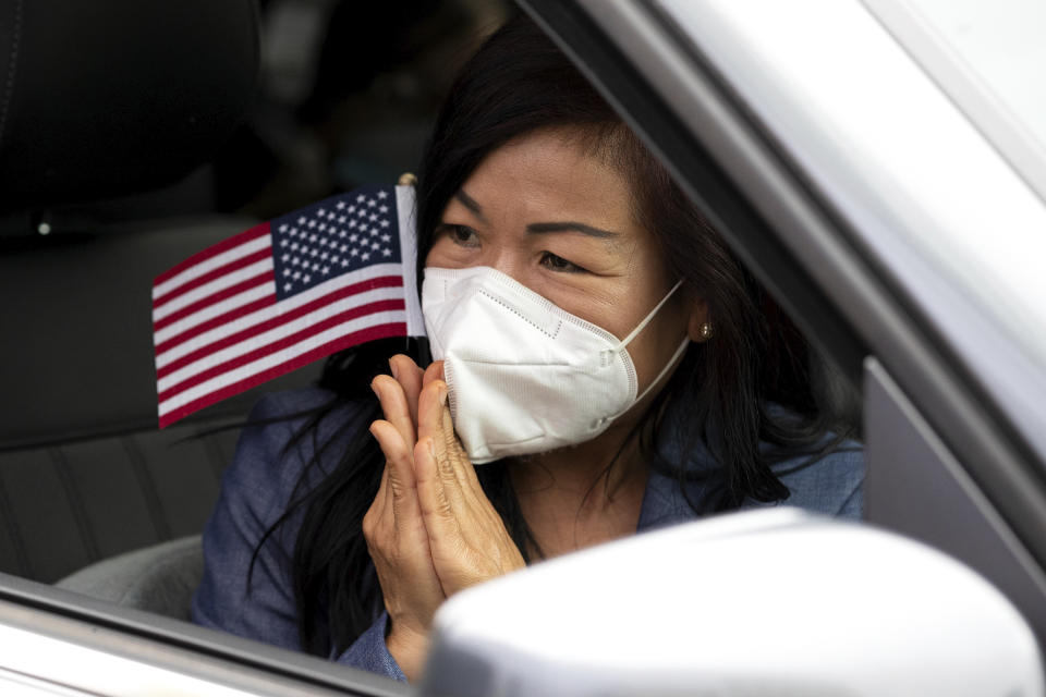 Hathairat Bees Roffers Duangsui, a Thailand native, reacts while holding a small American flag after reciting the citizenship oath during a drive-up naturalization ceremony outside the William J. Nealon Federal Building and United States Courthouse on North Washington Avenue in downtown Scranton, Pa. on Friday, July 17, 2020. (Christopher Dolan/The Times-Tribune via AP)