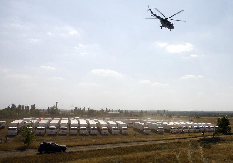 A helicopter flies over trucks from a Russian humanitarian convoy parked on a field outside the town of Kamensk-Shakhtinsky in the Rostov region, some 30kms from the Russian-Ukrainian border on August 14, 2014