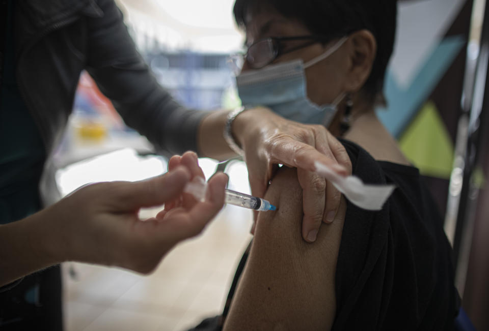 A woman receives her second dose of the Sinovac COVID-19 vaccine at the Carmela Carvajal public school in Santiago, Chile, Wednesday, March 10, 2021. (AP Photo/Esteban Felix)