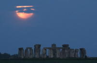 <p>The full moon, known as the "Super Flower Moon", is seen behind Stonehenge stone circle near Amesbury, Britain, May 26, 2021. REUTERS/Peter Cziborra</p> 