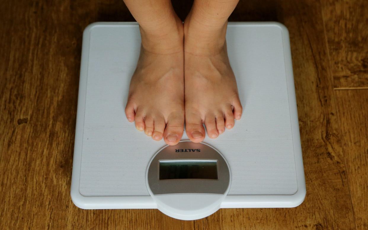 A young child stands on scales - PA