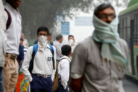 A schoolboy covers his face with a handkerchief as he waits for a passenger bus on a smoggy morning in New Delhi, India, November 8, 2017. REUTERS/Saumya Khandelwal