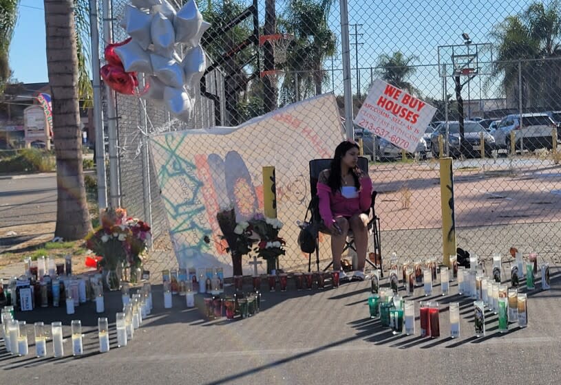 Friends leave flowers and candles on Monday at a parking lot in Compton near N Bullis Road, a day after two Latino men were shot and killed in a car that was parked near an illegal street takeover.