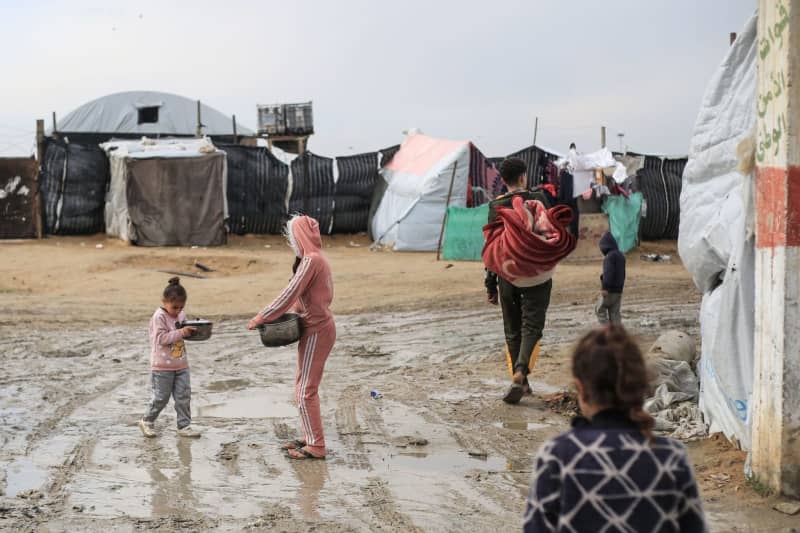 Palestinian children hold pots to fill them with water from a tank in a camp for IDP near Rafah border crossing, amid the ongoing battles between Israel and the Palestinian Islamist group Hamas. Mohammed Talatene/dpa