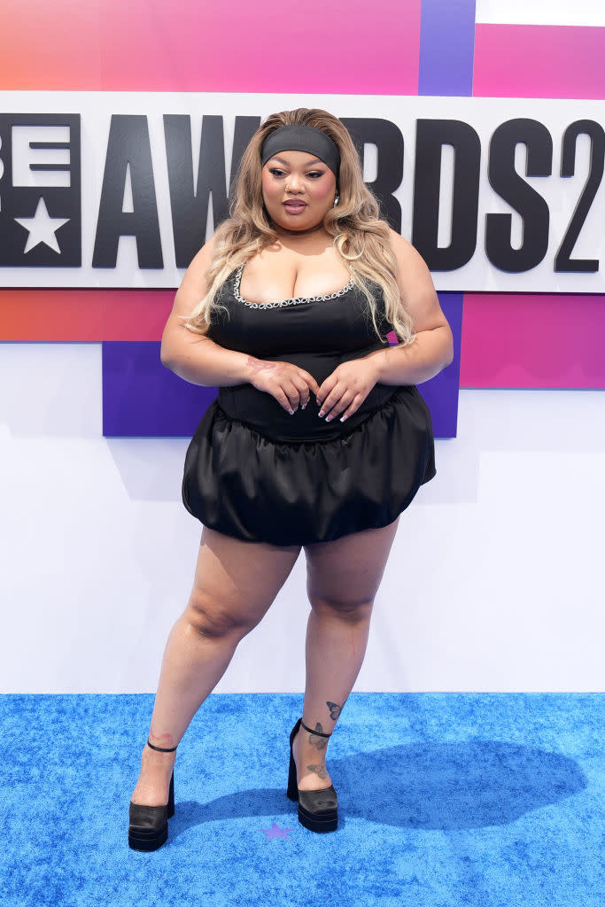 Maiya the Don at the BET Awards 2021, wearing a black mini dress with a cinched waist, black heels, and a black headband