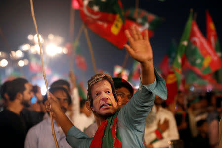 FILE PHOTO: A supporter of Imran Khan, chairman of the Pakistan Tehreek-e-Insaf (PTI), political party, wears a mask and dance on party songs during a campaign rally ahead of general elections in Karachi, Pakistan July 22, 2018. REUTERS/Akhtar Soomro/File Photo