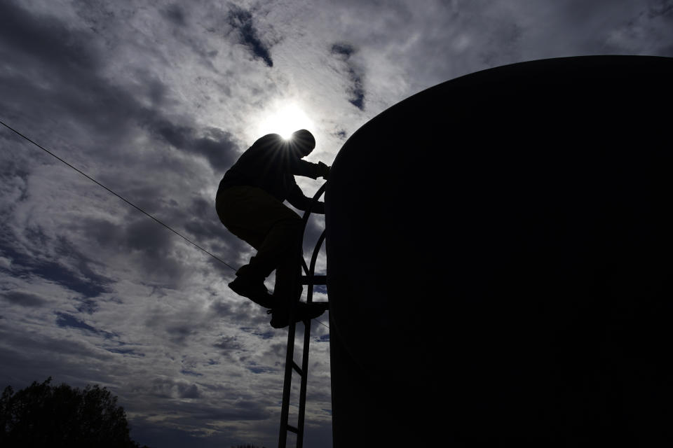 Garnett Querta checks a tank on his water truck on the Hualapai reservation Monday, Aug. 15, 2022, in Peach Springs, Ariz. The water pulled from the ground here will be piped dozens of miles across the rugged landscape to serve the roughly 600,000 tourists a year who visit the Grand Canyon on the Hualapai reservation in northwestern Arizona — an operation that's the tribe's main source of revenue. (AP Photo/John Locher)