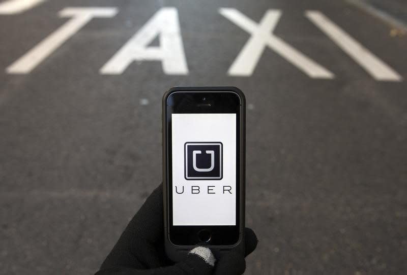 The logo of car-sharing service app Uber on a smartphone over a reserved lane for taxis in a street is seen in this photo illustration taken in Madrid on December 10, 2014. REUTERS/Sergio Perez/Files