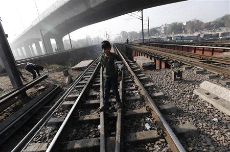 A ragpicker boy smiles as he stands on the tracks at a railway station in New Delhi February 18, 2014. REUTERS/Adnan Abidi